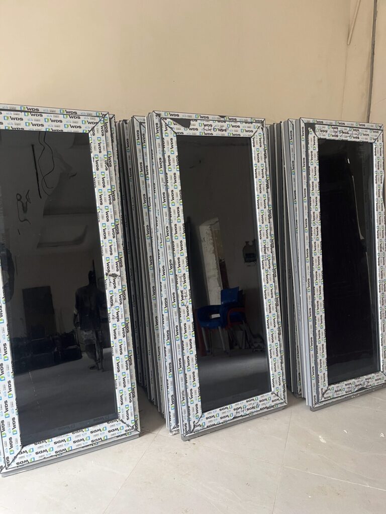 Newly glazed window sashes still wrapped in protective film, stacked at the Rotex factory