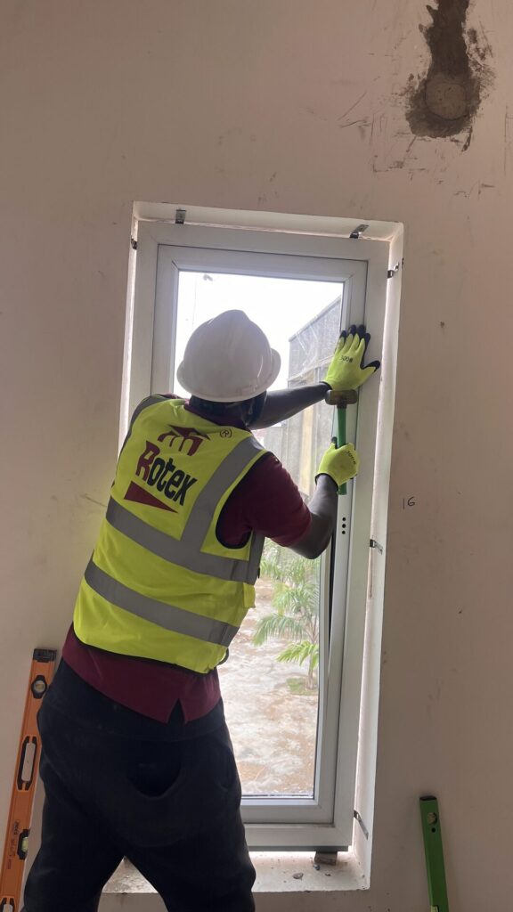A Rotex installer levelling a window frame in the opening before fixing it in place